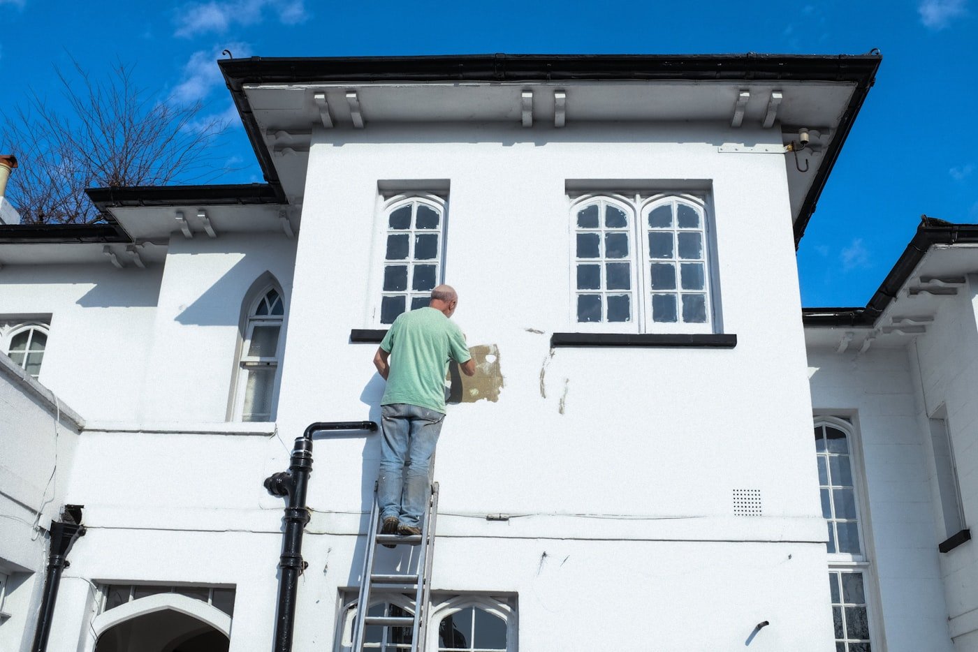 Painter on a ladder painting a home exterior