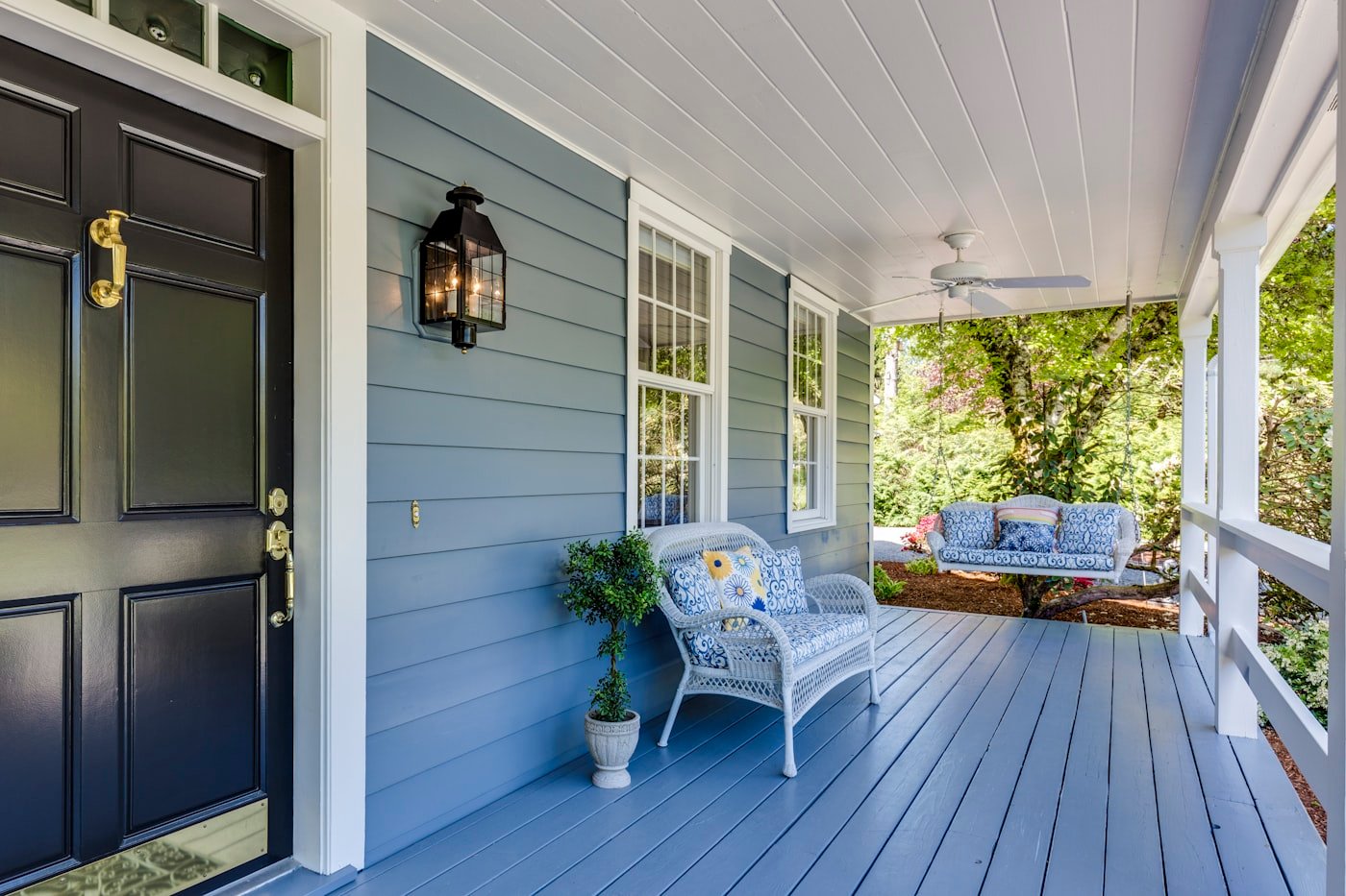 Blue-grey home with navy front door and white porch
